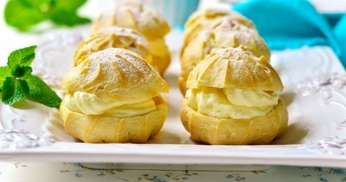 Assortiment de choux sucrés – pâtisseries légères garnies de crème parfumée, présentées avec soin sur plateau, parfaites pour une pause gourmande ou un dessert raffiné au bar.
