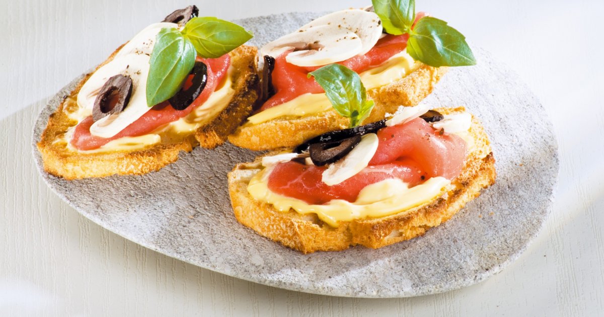 Tartines carpaccio, cheddar et oignon – tranches de pain toasté garnies de carpaccio de bœuf, lamelles de cheddar fondant et oignons caramélisés, pour une pause savoureuse et généreuse au bar.