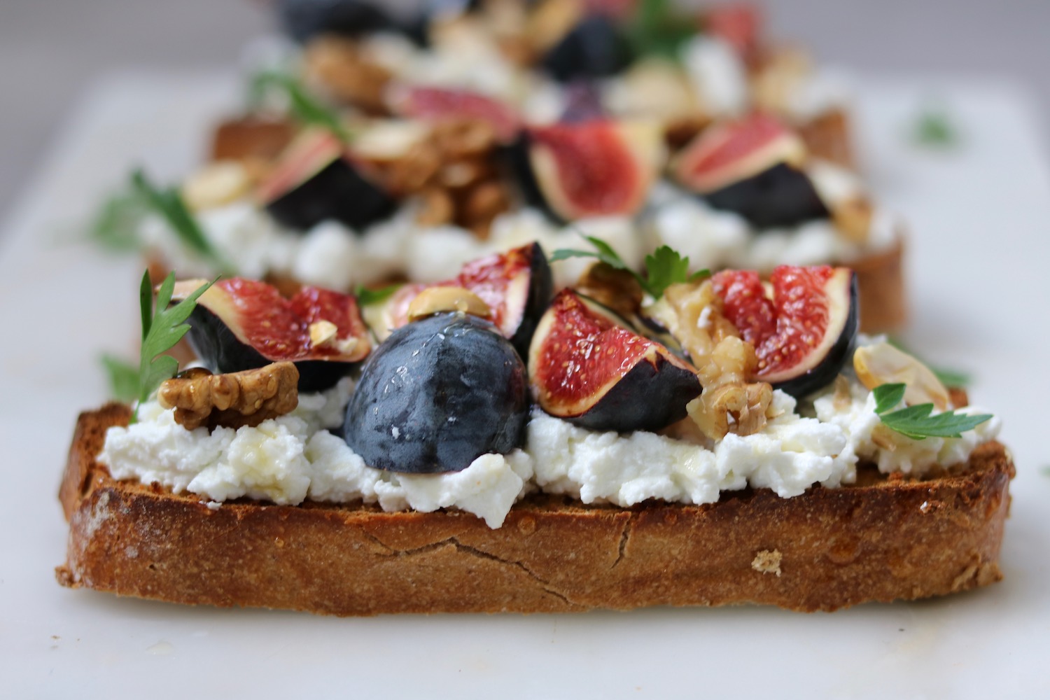 Tartines figues, jambon et noix – tranches de pain croustillant garnies de figues fraîches, jambon sec et éclats de noix, servies avec raffinement pour une pause salée-sucrée au bar.