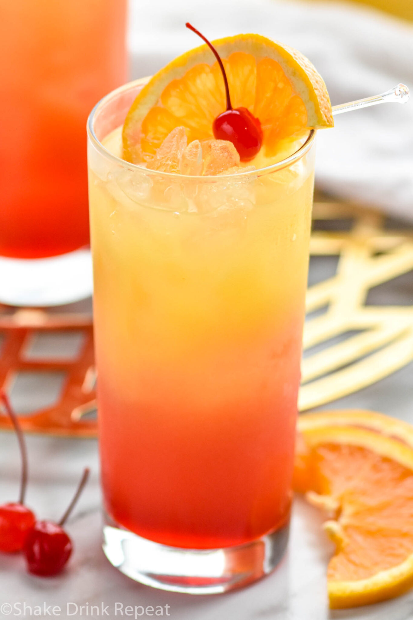 Cocktail Tequila Sunrise – mélange coloré de tequila, jus d’orange et sirop de grenadine, servi dans un verre transparent avec effet dégradé, évoquant un lever de soleil tropical et festif.